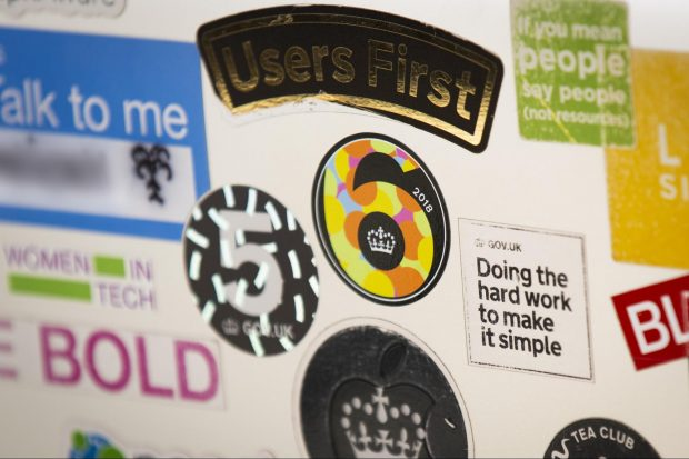 Laptop with several stickers on it. Some of the visible stickers read users first, doing the hard work to make it simple and women in tech.